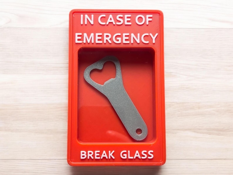 May include: Red break glass box with the text "IN CASE OF EMERGENCY" and "BREAK GLASS" in white lettering. A silver bottle opener is inside the box.