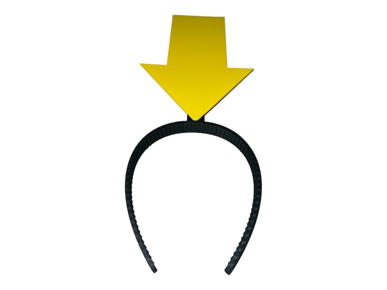 May include: A black plastic headband with a yellow arrow pointing downward. The arrow is a solid color and is attached to the top center of the headband. The headband is a simple, curved design.