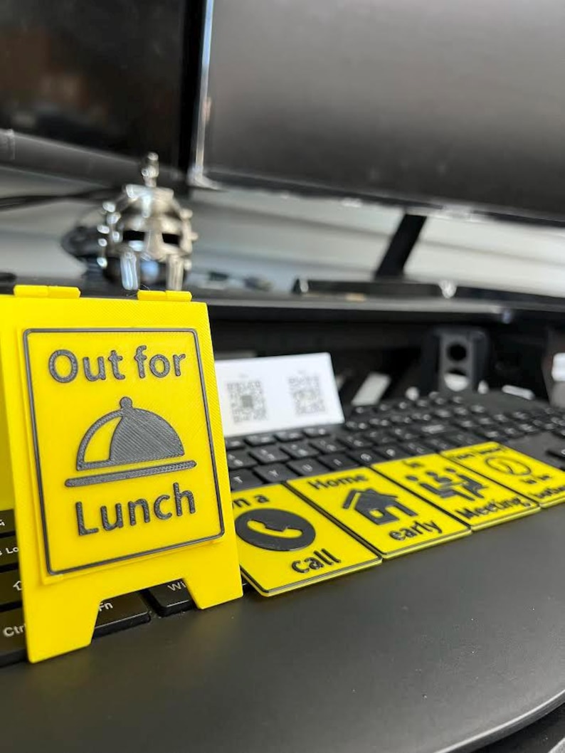 May include: A yellow sign with the text "Out for Lunch" and a graphic of a covered plate. Several yellow rectangular cards with black icons and text, including "Call", "Home", and "Meeting", are also visible.