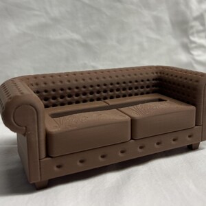 May include: A brown, tufted, two-seater sofa with a wood grain pattern on the cushions.