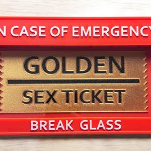 May include: Red break glass box with the text "IN CASE OF EMERGENCY" on the top and "BREAK GLASS" on the bottom. Inside the box is a gold ticket with the text "GOLDEN SEX TICKET" in black.