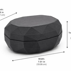 Puede incluir: Una caja negra de forma geom&eacute;trica con un dise&ntilde;o facetado. La caja mide 19,08 cm de ancho, 13,11 cm de profundidad y 7,62 cm de alto. La caja est&aacute; hecha de un material oscuro y tiene tapa.