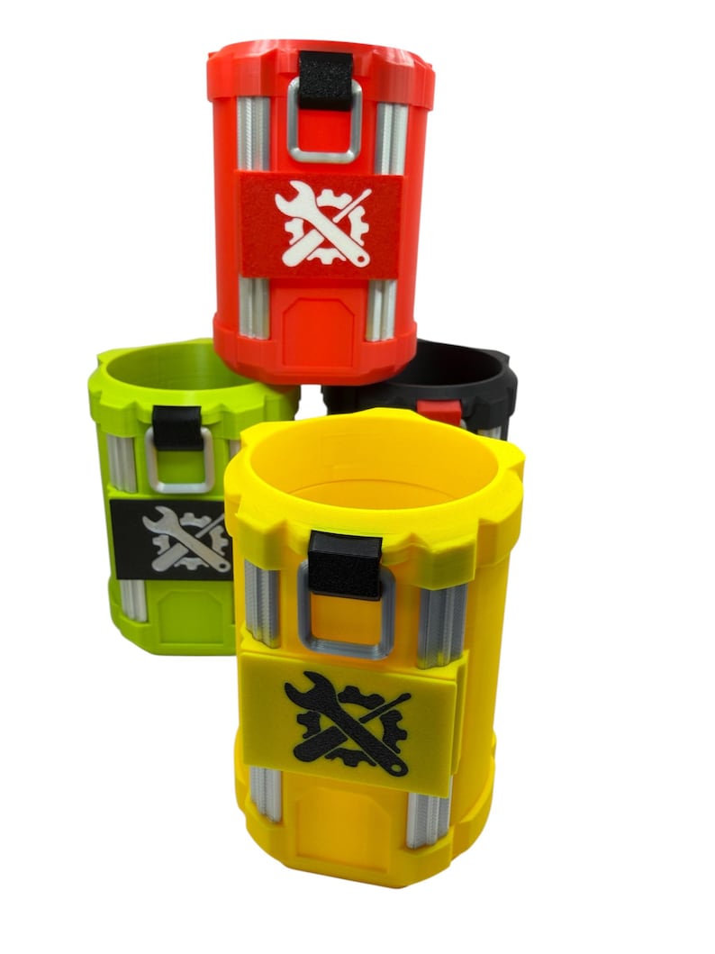 May include: A collection of four cylindrical containers in red, yellow, lime green, and black. Each container features vertical silver-colored accents, a black top handle, and a central rectangular patch displaying a white or black wrench and gear icon.