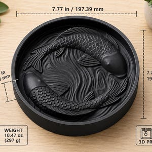 Puede incluir: Una bandeja decorativa negra y redonda con un dise&ntilde;o en relieve de dos peces koi nadando en un patr&oacute;n de olas. La bandeja tiene 197.39 mm de di&aacute;metro y 31.73 mm de profundidad. Pesa 297 g y est&aacute; impresa en 3D.