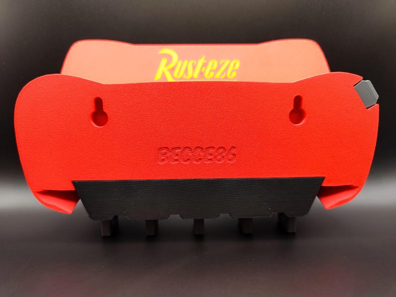 May include: Red and black wall-mounted shelf with the word "Rusteze" in yellow. The shelf has two keyhole slots for hanging and the number "86C0E86" printed on the front. The shelf has a black base with several small, rectangular supports.