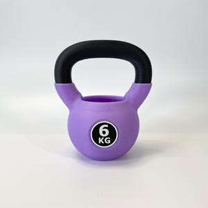 May include: A purple kettlebell with a black handle. The weight is indicated as 6 KG on a white and black circular sticker. This fitness equipment is designed for strength training and exercise routines.