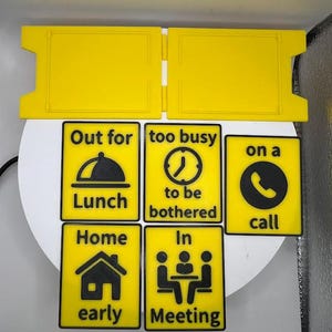 May include: Yellow and black signs with various messages, including "Out for Lunch," "Too busy to be bothered," and "On a call." Other signs read "Home early" and "In Meeting." The signs are designed to be easily visible.