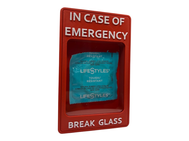 May include: A red emergency box with the words "IN CASE OF EMERGENCY" and "BREAK GLASS" in white. Inside the box is a blue and white Lifestyles condom package. The package reads "TOUGH/RESISTANT".