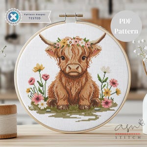 May include: A cross-stitch pattern of a Highland cow wearing a floral crown, surrounded by flowers. The design is set in a wooden embroidery hoop. The text "PDF Pattern" is visible. The words "Pattern Keeper Tested" and "asn STITCH" are also visible.