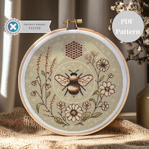 May include: A cross-stitch pattern featuring a bee surrounded by flowers and a honeycomb. The pattern is in a hoop and has a beige background with brown, yellow, and green accents. The text "PDF Pattern" is in the top right corner of the image.