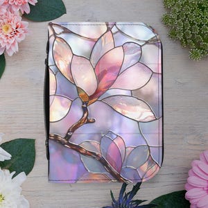 May include: A zippered case with a stained-glass floral design. The design features a magnolia flower in shades of pink, purple, and white, with brown stems and a black border. The case is set against a light wood background with flowers.