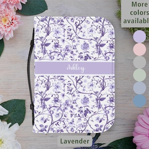 Op de afbeelding: Een boekcover met een lavendelkleurig bloemenpatroon en de naam "Ashley" in script. Het heeft een zwarte band en de tekst "Meer kleuren beschikbaar". Het woord "Lavendel" staat onderaan. De achtergrond bevat bloemen.