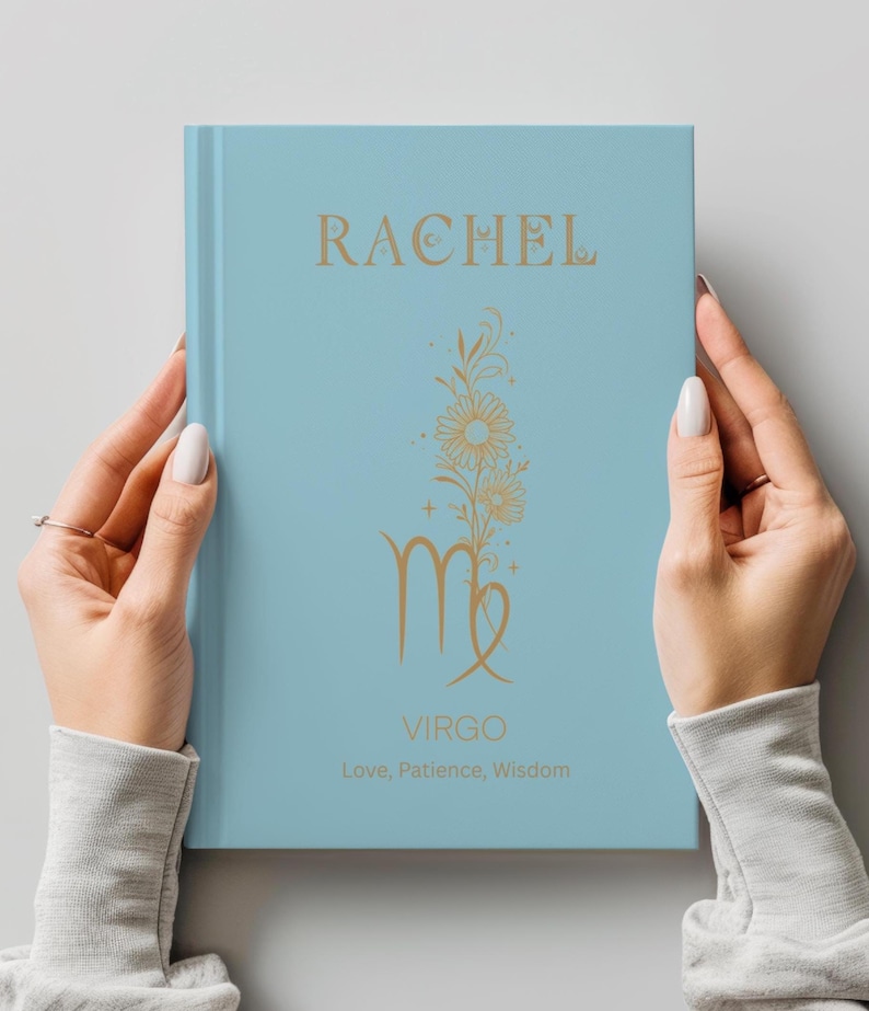 May include: A light blue hardcover book featuring gold foil text and graphics. The cover displays the name RACHEL, a floral illustration, the word VIRGO, and the text Love, Patience, Wisdom. The design includes celestial symbols and stars.