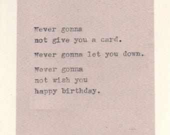 May include: A pale pink birthday card with the text "Never gonna not give you a card. Never gonna let you down. Never gonna not wish you happy birthday." Decorative swirls in each corner.
