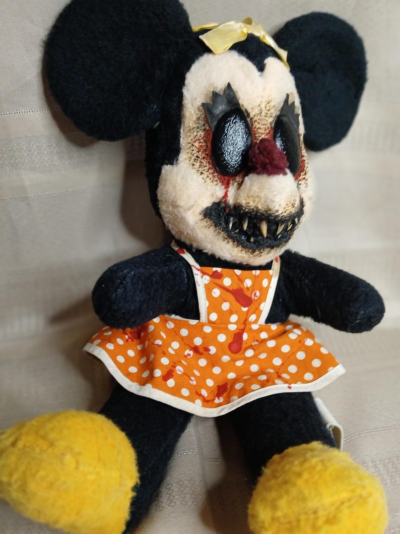May include: A creepy, handmade plush doll with black ears, a yellow bow, and a sinister expression. The doll wears an orange polka-dot apron with red splatters. Yellow shoes complete the unsettling look.