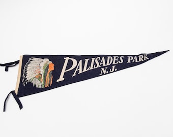 May include: Navy blue pennant with the words "PALISADES PARK N.J." in white. An illustration of a Native American chief in profile is on the left side. The pennant has black ties.