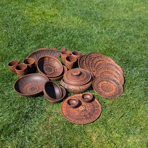 Könnte beinhalten: Ein Set aus braunen Tontellern und -schalen mit aufwendigen Designs. Das Set enthält Teller, Schalen und Tassen, alle aus Steingut.