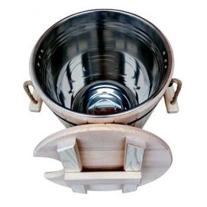 Può includere: Un secchio di legno con interno in acciaio inossidabile, con un coperchio in legno abbinato. Il secchio ha manici in corda ed è progettato per contenere liquidi. Il coperchio è parzialmente aperto, rivelando l'interno.