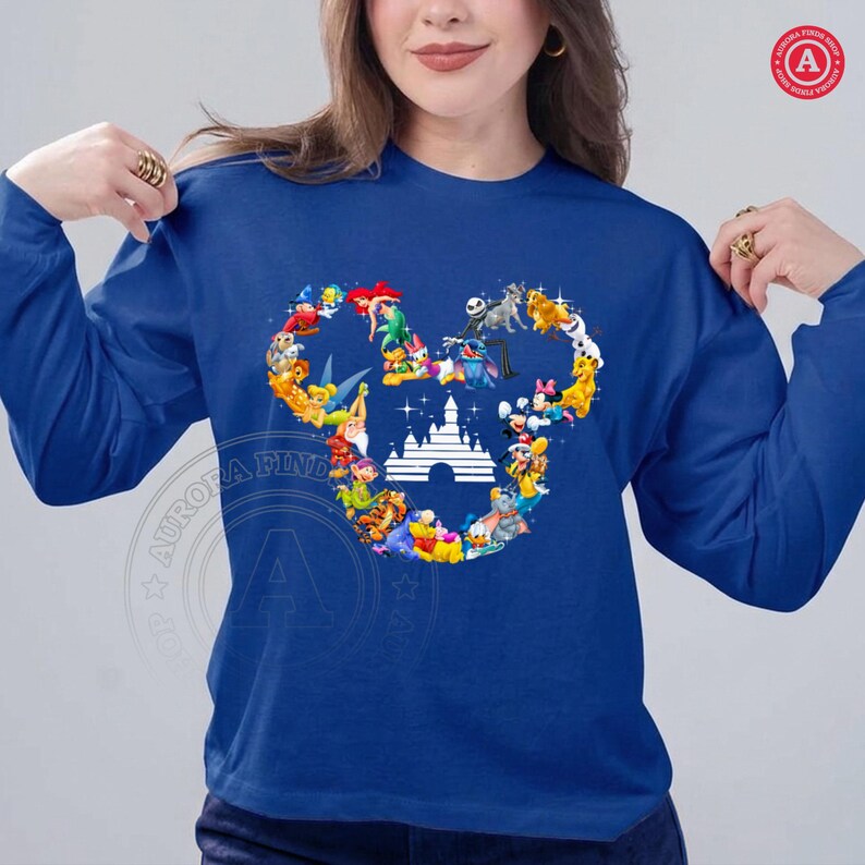 Peut inclure: Un sweat-shirt bleu roi &agrave; manches longues avec un motif de t&ecirc;te de Mickey Mouse compos&eacute; de divers personnages Disney. Le motif comprend des personnages comme Ariel, Jack Skellington et Mickey Mouse, avec une silhouette de ch&acirc;teau blanc au centre.