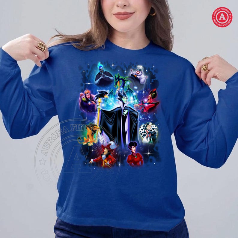 May include: A royal blue long-sleeved top with a graphic featuring various Disney villains. The design includes characters such as Maleficent and Cruella de Vil. The top has a round neck and is made of a soft fabric.