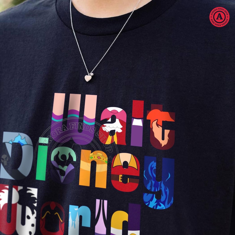 Puede incluir: Camiseta negra con un gr&aacute;fico colorido de "Walt Disney World". Se lleva un collar de plata con un colgante de coraz&oacute;n sobre la camiseta. El gr&aacute;fico presenta varios personajes y elementos de Disney.