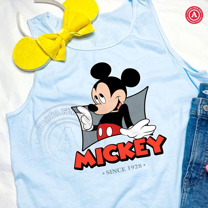 May include: Light blue tank top featuring a Mickey Mouse graphic. The graphic includes Mickey Mouse in black, red, and white, with the word "MICKEY" in red and the text "SINCE 1928." A yellow bow and mouse ears headband are also visible.