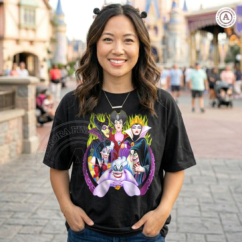 May include: Black t-shirt featuring a colorful graphic of Disney villains, including Ursula, Maleficent, and the Evil Queen. The design is surrounded by green flames and purple tentacles. The shirt is worn by a person in an outdoor setting.
