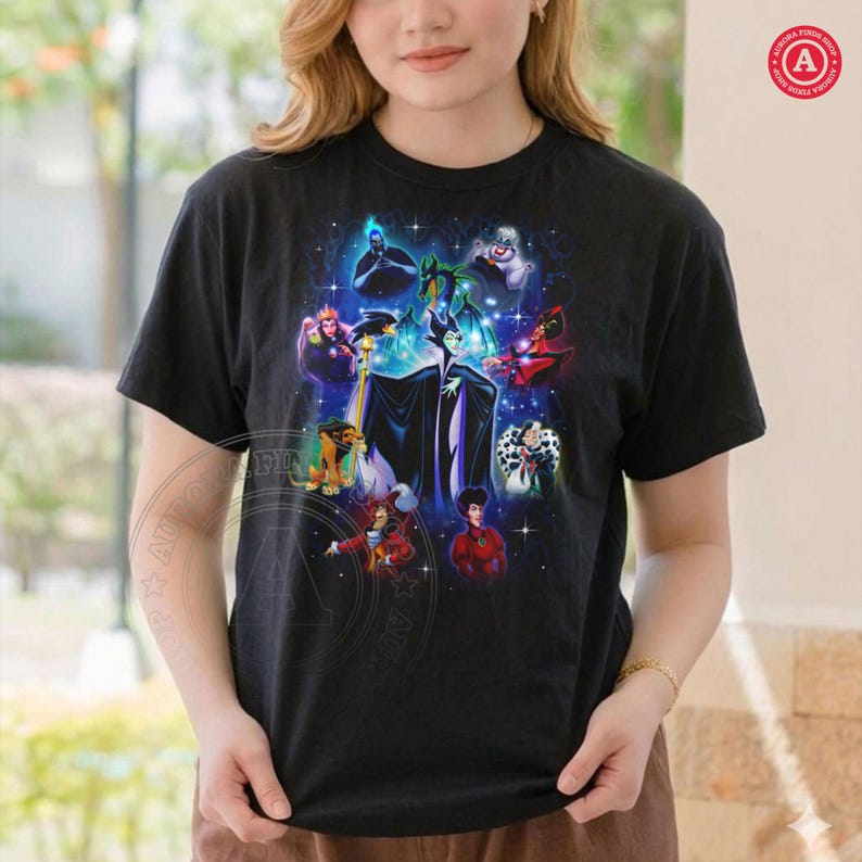 May include: Black t-shirt with a vibrant graphic of animated villains, including Maleficent, Cruella de Vil, and the Evil Queen. The design is set against a dark background. The t-shirt has a crew neck and short sleeves.