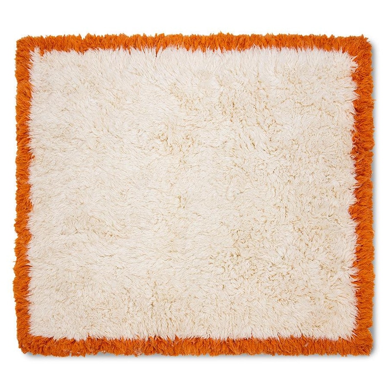Pode incluir: Um tapete de formato quadrado com um centro espesso e felpudo na cor creme, rodeado por uma borda laranja vibrante. Todo o per&iacute;metro do tapete &eacute; finalizado com uma borda texturizada com franjas que adiciona profundidade ao design da pe&ccedil;a.