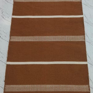 Handwoven brown striped polypropylene rug with fringe laid flat showing full design.