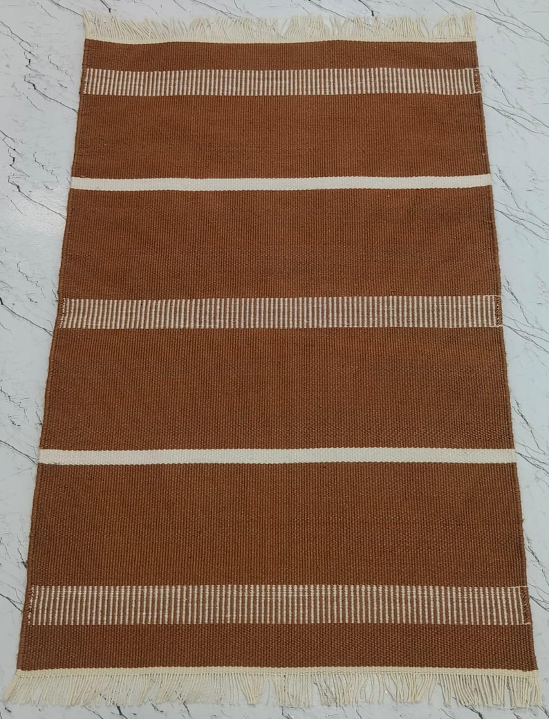 Handwoven brown striped polypropylene rug with fringe laid flat showing full design.