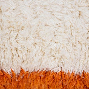 Pode incluir: Um t&ecirc;xtil espesso de pelo alto com uma textura densa e felpuda. A parte superior &eacute; de cor creme esbranqui&ccedil;ado, enquanto a sec&ccedil;&atilde;o inferior transita para um tom laranja vibrante e s&oacute;lido. As fibras s&atilde;o longas, macias e sobrepostas.