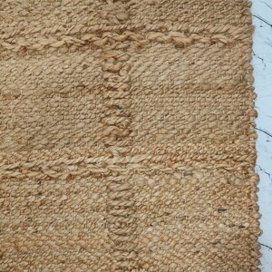 Rolled natural jute rug showing thickness and durable flatweave construction.