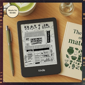 May include: A black Kindle e-reader displaying a black and white illustration of a Japanese shop with the text "Matcha & Book Corner". A green pen and a book titled "The of matcha" are next to the e-reader.