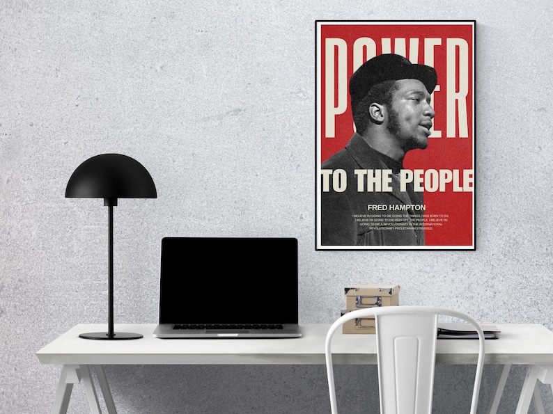 Fred Hampton print displayed on a workspace desk with a lamp and laptop. A bold, thought-provoking digital print for modern office and study spaces.