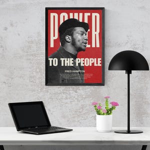 Fred Hampton print displayed on a workspace desk with a lamp and laptop. A bold, thought-provoking digital print for modern office and study spaces.