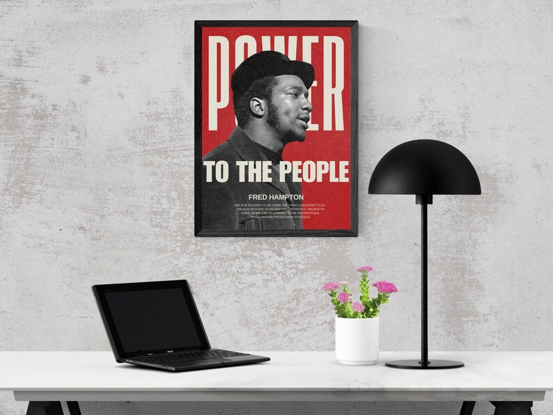 Fred Hampton print displayed on a workspace desk with a lamp and laptop. A bold, thought-provoking digital print for modern office and study spaces.