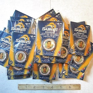 May include: A collection of Buffalo Sabres hockey trading cards featuring various players from the 2006-2007 season. The cards are blue and yellow with a silver medallion in the center. The text on the cards reads "Officially Licensed 2006-07 Medallion Collection".