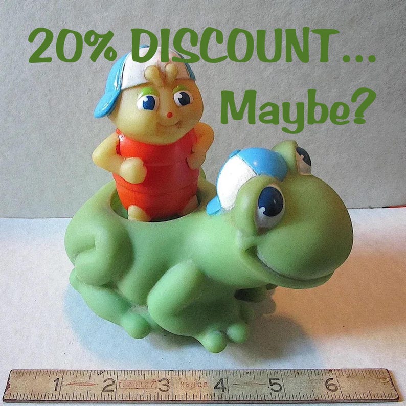 Puede incluir: Un juguete vintage que presenta una figura amarilla con forma de insecto con una parte superior roja y una gorra azul montada en una rana verde. El texto "20% DISCOUNT... Maybe?" est&aacute; escrito en verde encima de las figuras. Una regla est&aacute; en la parte inferior.