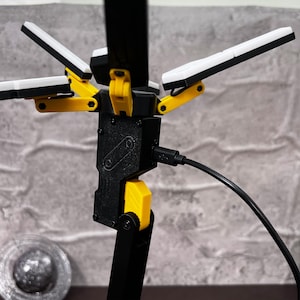 The Death Stranding inspired folding LED lamp is a stylish and practical addition to any space. With its futuristic design, this lamp features an adjustable structure that can be posed in various ways to suit your lighting needs. Made with high-quality PLA material, this 3D printed lamp showcases durability and attention to detail. The unique color combination of yellow, black, and metallic silver ties back to the Bridges organization seen in the Death Stranding game