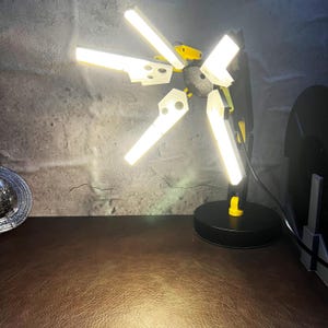 This adjustable Death Stranding inspired folding LED lamp is perfect for those who love both video games and unique home decor. The lamp’s folding design makes it easy to store and travel with, allowing for convenient use in any setting. With warm LED lighting, the lamp can create the perfect atmosphere for gaming, reading, or relaxation. The Odradek scanner replica design adds an extra level of detail for fans of the game, making it a must-have collector’s item.