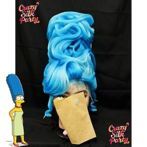 Puede incluir: Una peluca azul vibrante, peinada con rizos voluminosos, exhibida en una cabeza de maniquí. La peluca es de un tono azul brillante y llamativo. El texto "Crazy Silk Party" es visible en las esquinas superior izquierda e inferior derecha.