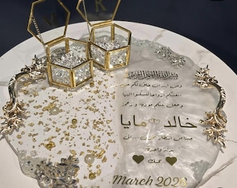 May include: A decorative tray with gold accents, featuring two hexagonal glass boxes filled with crystals. The tray has gold handles and is adorned with gold leaf and text that reads "March 2026".