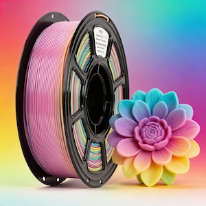 May include: A spool of pink 3D printing filament next to a colorful, multi-layered flower. The filament is on a black spool. The flower has petals in shades of blue, purple, pink, yellow, and green.