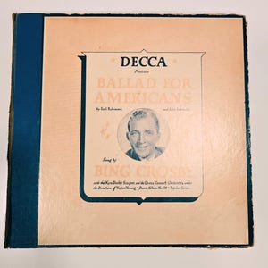 May include: Vintage vinyl record album cover for "Ballad for Americans" by Bing Crosby, presented by Decca. The cover features a portrait of Crosby, with text in a decorative frame on a light peach background, and a blue spine.