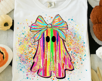 May include: White t-shirt featuring a colorful ghost design with a large bow. The ghost is decorated with rainbow stripes and gold glitter accents. The design is surrounded by colorful paint splatters.