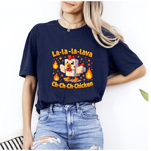 May include: Navy blue t-shirt with a cartoon chicken design. The design features a pixelated chicken with flames and the text "La-la-la-lava" and "Ch-Ch-Ch-Chicken" in orange and yellow.