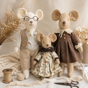 May include: Three stuffed fabric mice dolls. The left mouse wears a striped shirt, tan vest, and pants with round glasses. The center mouse wears a floral dress with a dark collar. The right mouse wears a brown dress with a white lace collar.