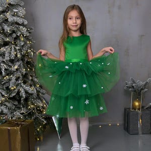 christmas tree cake dress Beautiful Woman Standing in a Green Dress Near a Christmas Tree and Holding a Cake in Her Hands Stock Photo