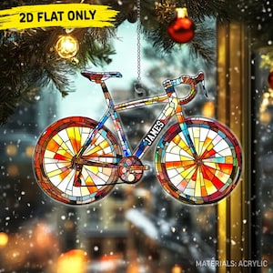 May include: A colorful, stained-glass style bicycle ornament. The bike features a vibrant design with red, yellow, blue, and green hues. The word "JAMES" is visible on the frame. The ornament is hanging from a chain, with the text "2D FLAT ONLY" visible.